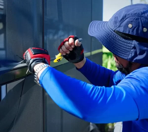 echnician in blue uniform expertly rescreening a pool cage enclosure with professional tools, showcasing quality craftsmanship and attention to detail.